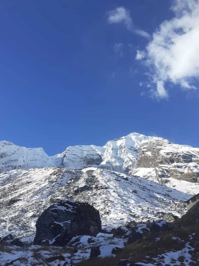 Rugged snow-capped mountain peaks towering over a rocky trekking trail in the Annapurna region