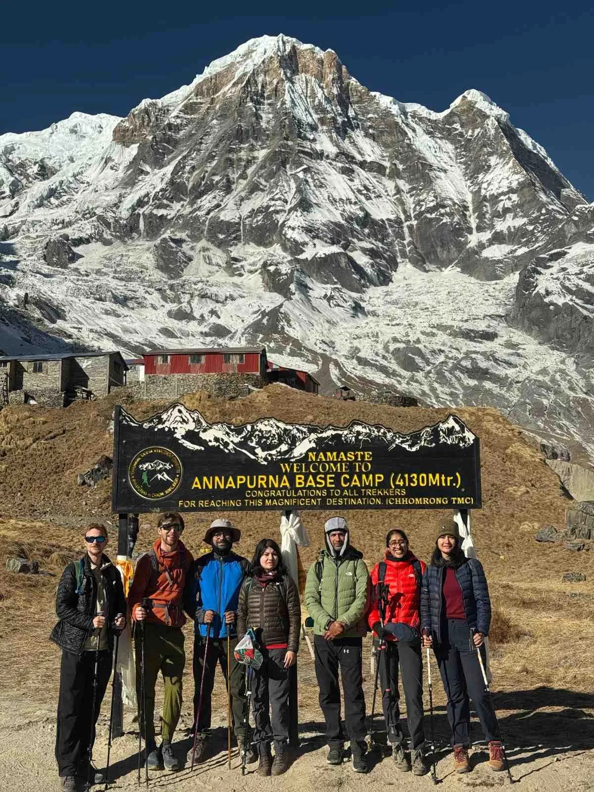 trekkers group standing beside Annapurna base camp sign board