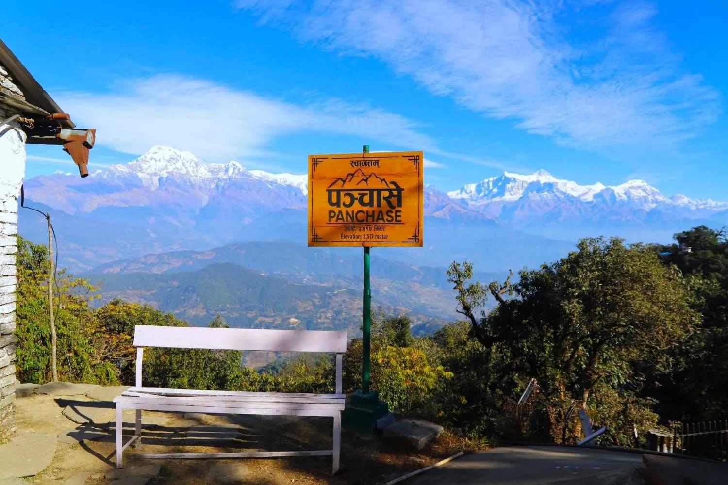 Panchase summit sign at 2517m with a white bench overlooking a vast vista of Himalayan peaks