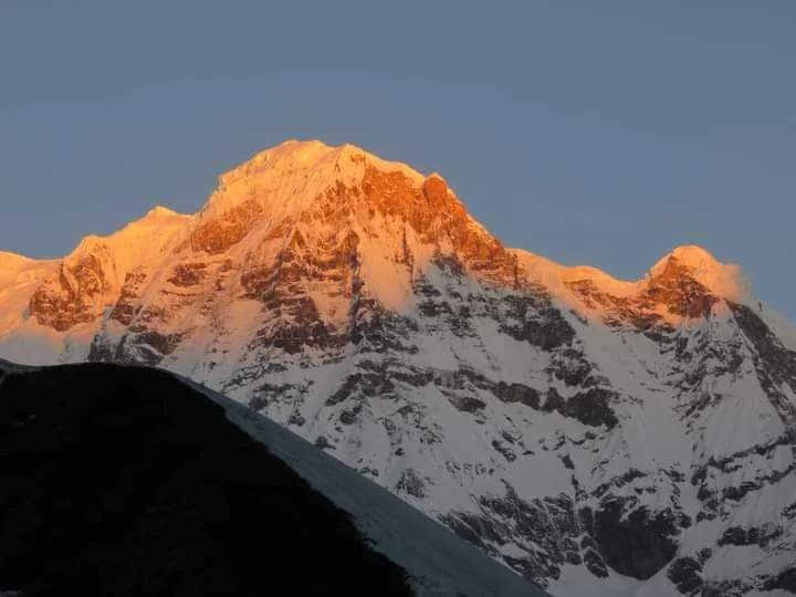 Golden sunset light hitting the snowy summit of Annapurna South during an ABC and Poon Hill trek