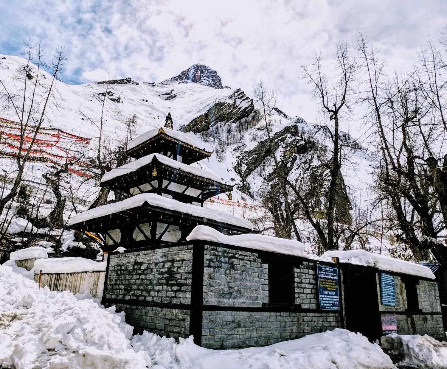 The multi-tiered Muktinath Temple covered in deep winter snow against a mountain backdrop