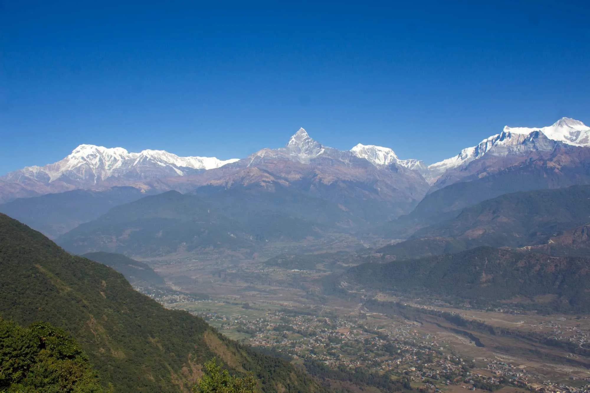 Panorama of the Annapurna mountain range and Machhapuchhre peak over a lush valley